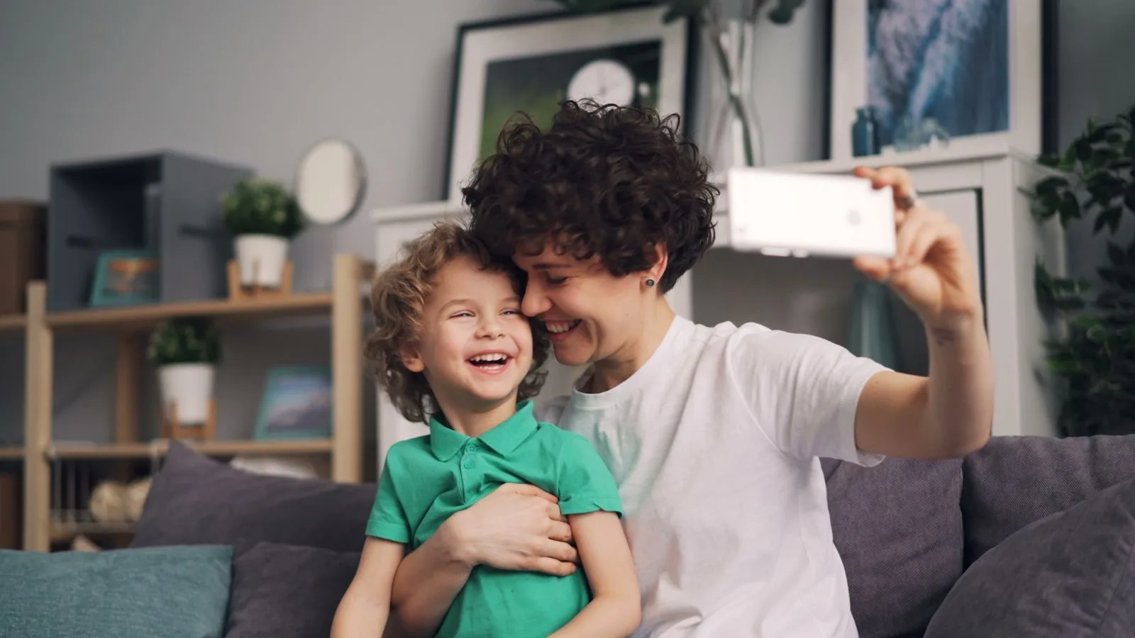 Compartilhar foto dos filhos na internet: cuidados de pais e familiares 1 A joyful moment of a mother and child taking a selfie together indoors. Smiling faces create a warm family bond.