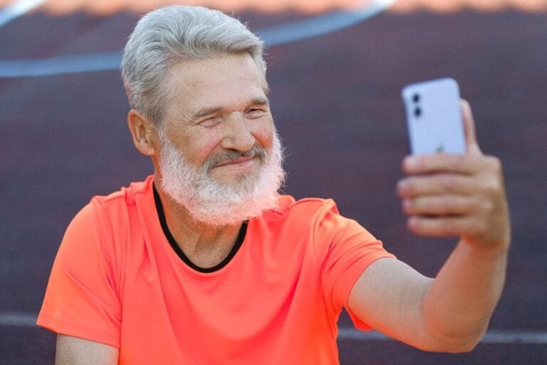 Consignado do INSS passa a exigir confirmacao por biometria facial no Meu INSS em ate 5 dias, a partir de 19/05/2026 9 Happy elderly man with white hair taking a selfie on a smartphone while outdoors.