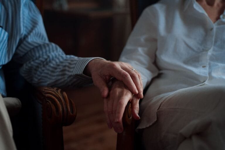 Como podemos ajudar? 12 An intimate moment of an elderly couple holding hands, capturing love and companionship.