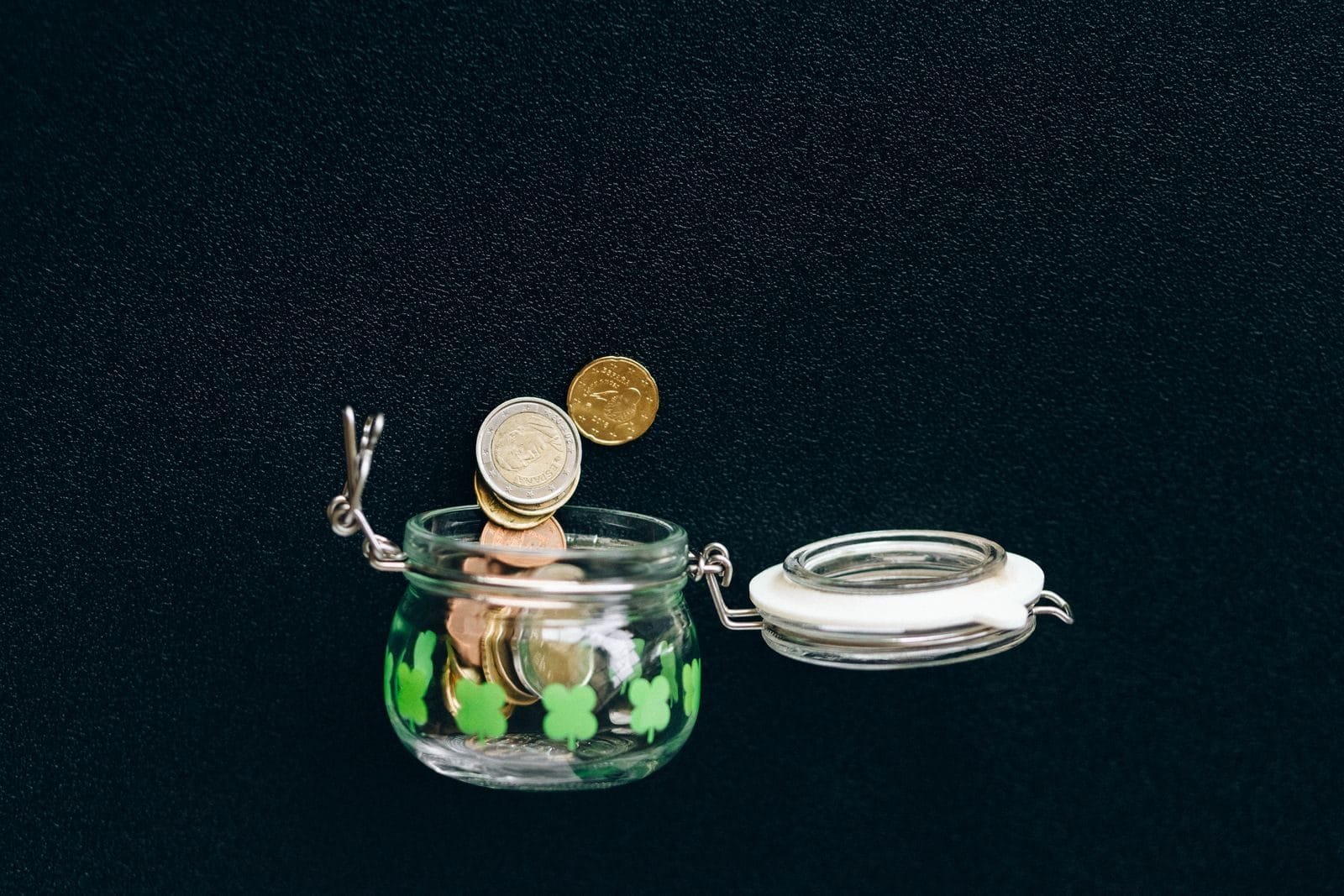 Quando Vale a Pena Contribuir como Facultativo em 2026 1 Glass jar with coins falling into it on a black background, symbolizing savings.