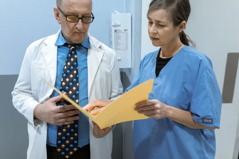 Convocação para Perícia do INSS: Documentos e Preparação 3 Doctor and nurse examining patient records in a clinical setting.