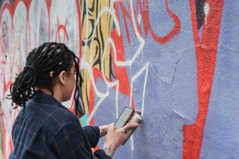 A person painting vibrant graffiti on a wall using spray paint outdoors.