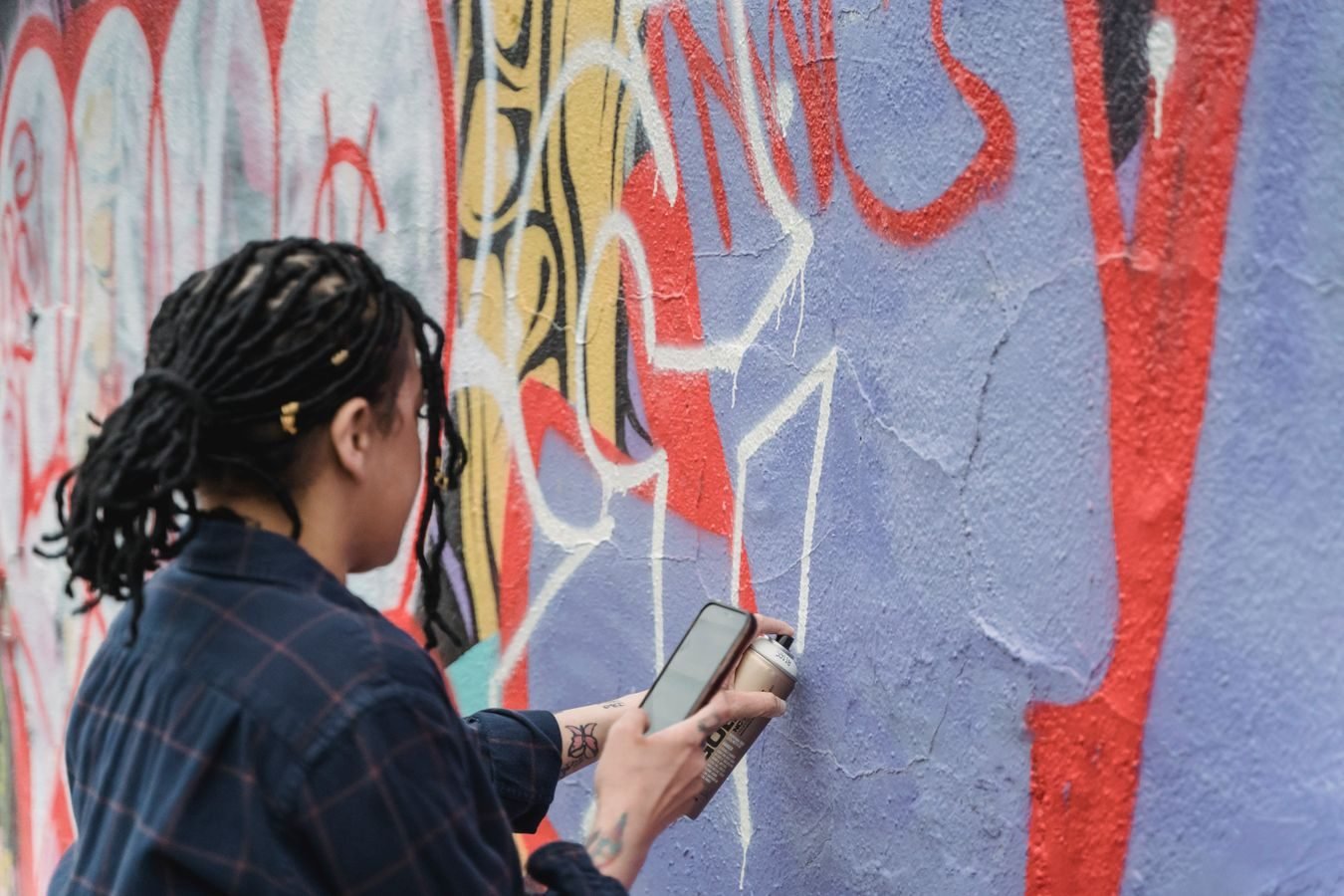 Dano ao patrimonio alheio: pichacao, depredacao e o dever de reparar 1 A person painting vibrant graffiti on a wall using spray paint outdoors.