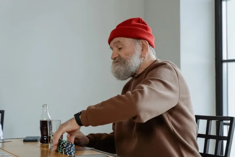 Senior man with beard playing poker at home, focused and relaxed.