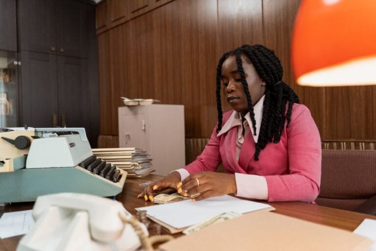 Descaracterização do cargo de confiança e a sétima hora do bancário 6 African American woman in business attire counting money at a vintage office desk.