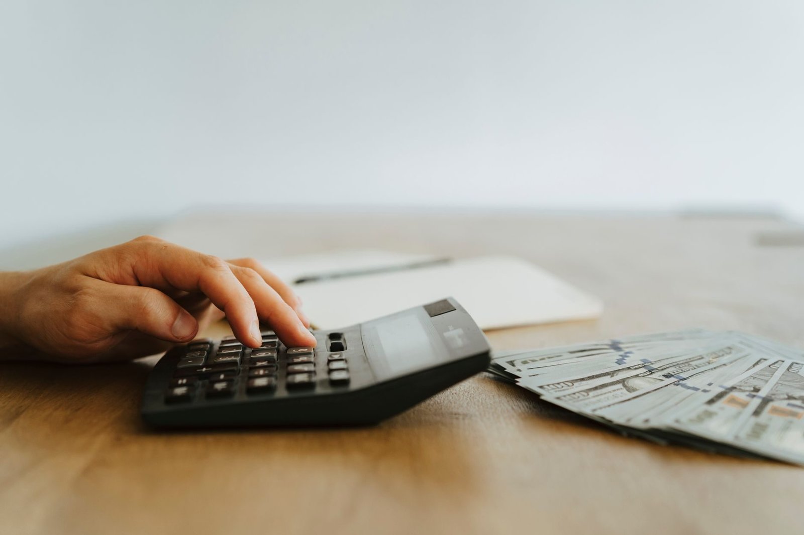 Desconsideracao da personalidade juridica no Direito Tributario 1 A hand calculating finances with a calculator next to stacks of US dollar bills.
