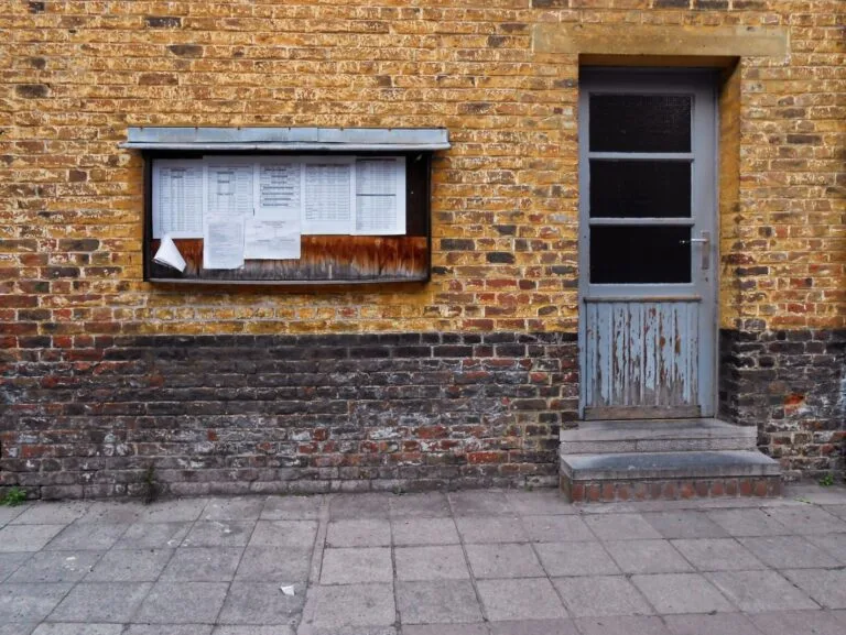 Despejo por falta de pagamento: como funciona e quais os direitos de cada lado 6 A rustic brick wall in Mons, Belgium, featuring a notice board and weathered door.