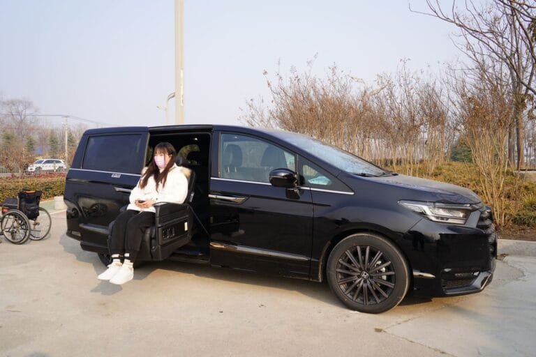 Woman in face mask using sliding seat in black car with nearby wheelchair.