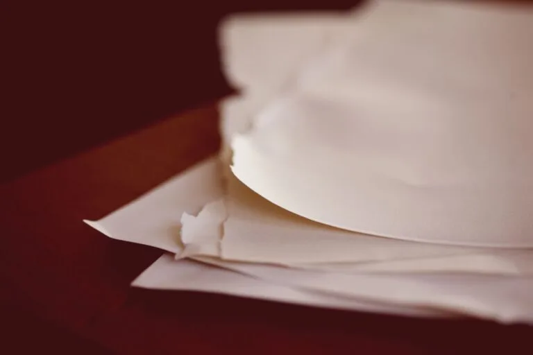 A close-up view of torn papers stacked on a desk with a blurred background.