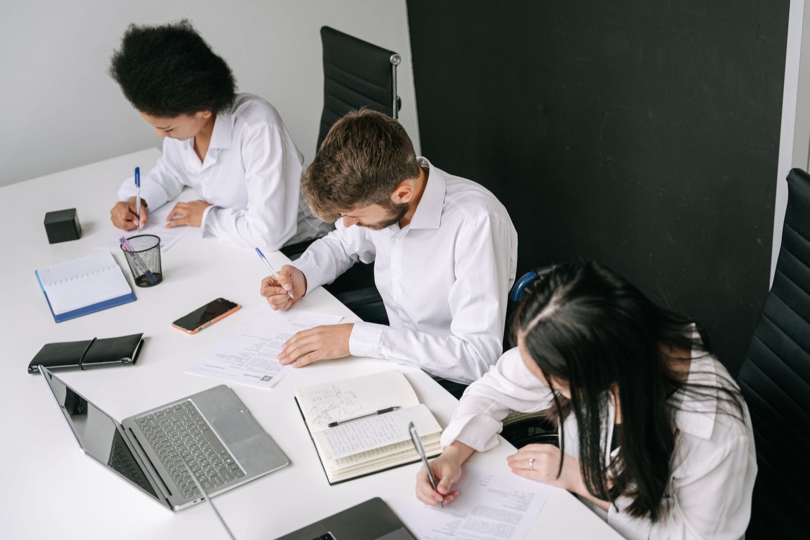 Diverse team working together in a sleek office with laptops and notebooks.