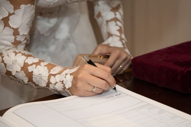 Divórcio Consensual: Passo a Passo Completo em 2026 5 Bride in lace dress signing marriage certificate at wedding ceremony.