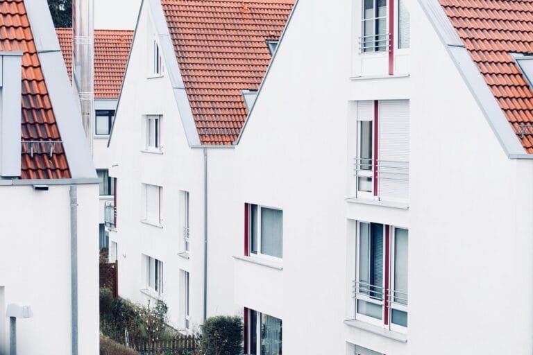 Due diligence na compra de imóvel: as certidões que evitam prejuízo no negócio 6 White houses with red roofs create a clean and modern suburban landscape.