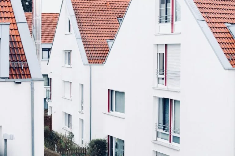 Due diligence na compra de imóvel: as certidões que evitam prejuízo no negócio 6 White houses with red roofs create a clean and modern suburban landscape.