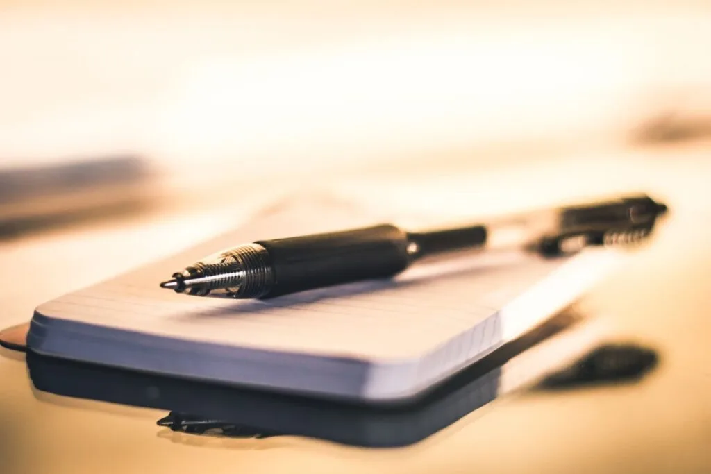 A família Souza superou a burocracia do inventário e regularizou o patrimônio 1 Close-up of a black ballpoint pen resting on an open lined notebook with warm lighting.