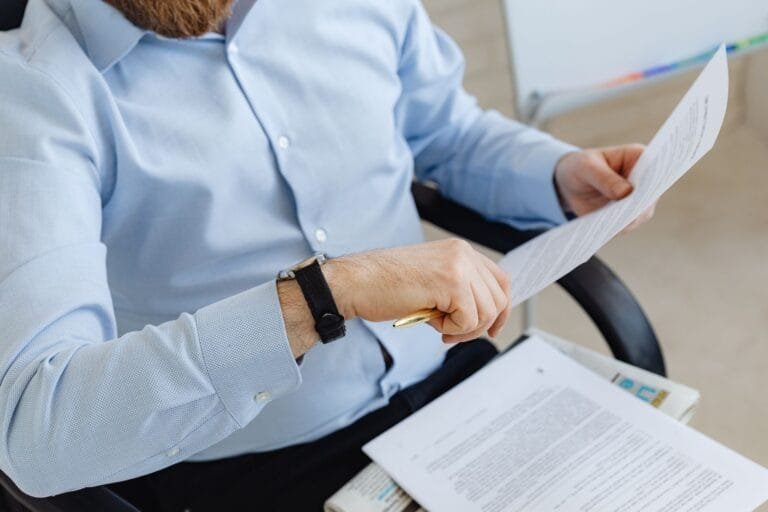 Businessman reviewing papers in office setting, highlighting analysis and attention to det
