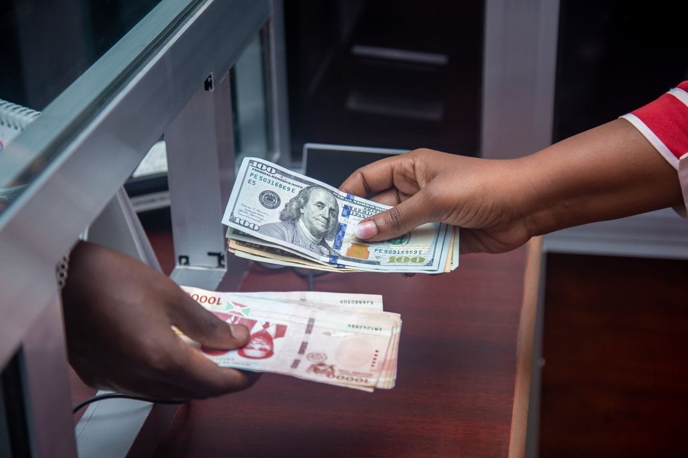 Gratificação de função do bancário e a terça parte do salário 1 Hands exchanging US and local currency at a bank counter, signifying international finance.