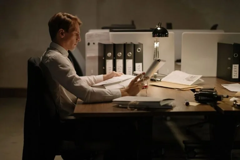 Gratificação de Desempenho: Incorporação ao Salário do Servidor 3 An office worker in formal attire intensely focused while reading documents at a desk with folders and a lamp.