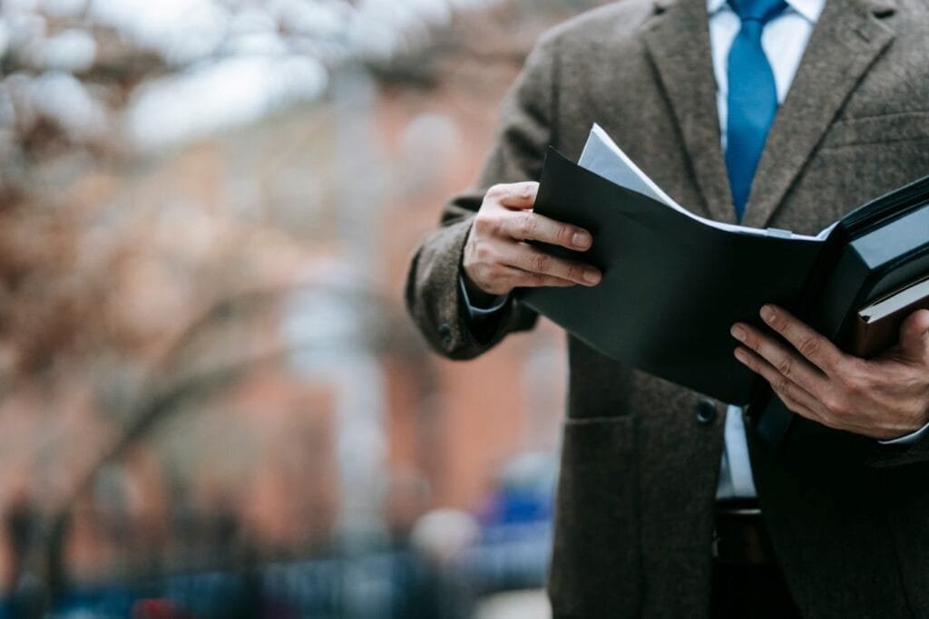 Passo a passo para entender o seu CNIS 1 A professional in formal wear reviewing documents outside, showcasing business attire and focus.