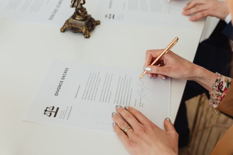Habilitação na licitação: documentos que costumam derrubar a proposta 7 Close-up of hands signing a divorce decree document on a desk, showcasing legal process.