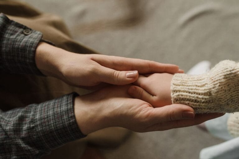 Como podemos ajudar? 5 Heartwarming image showing adult and child holding hands, symbolizing affection and care.