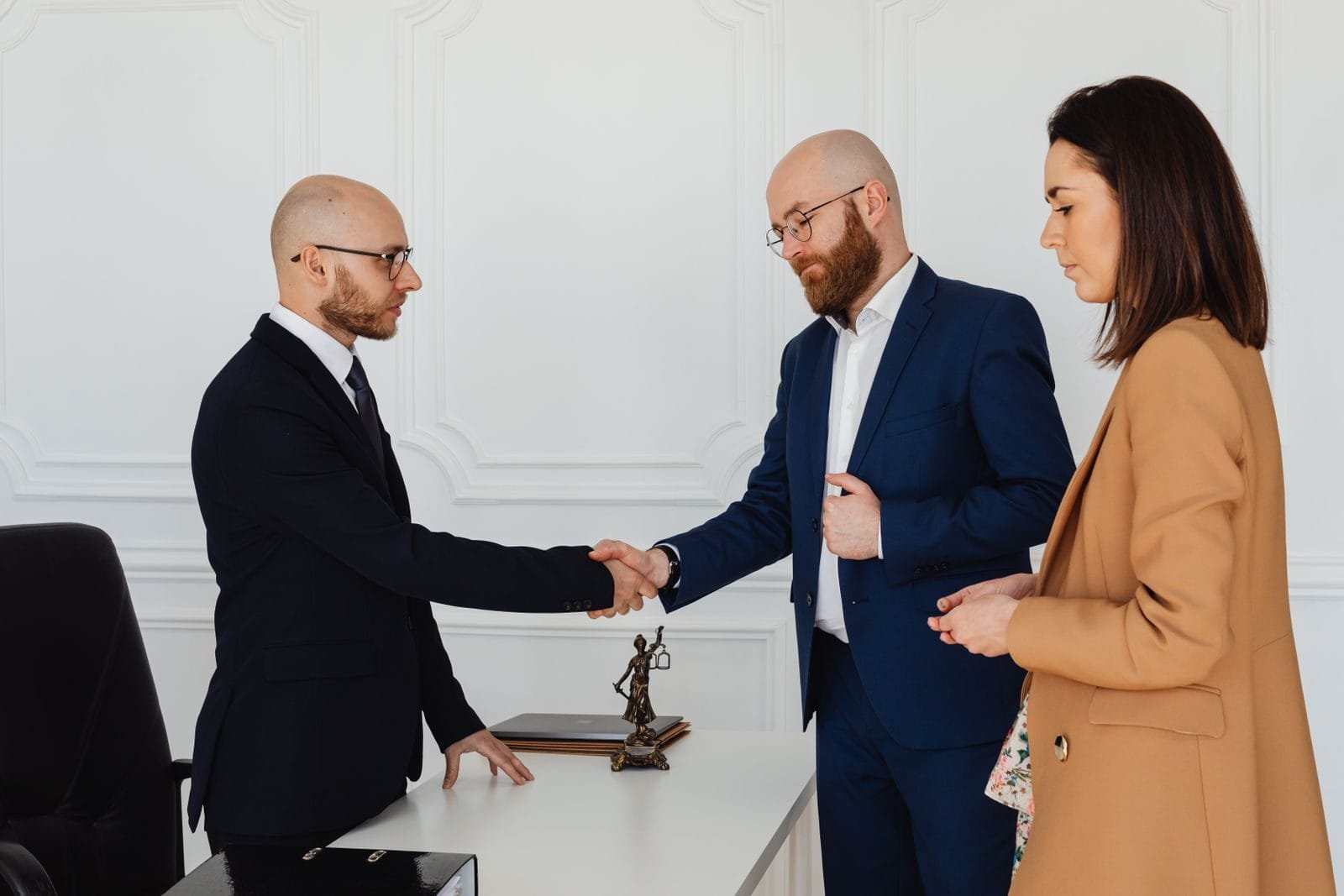Honorários transparentes: como entender e combinar o pagamento do advogado 1 Three business professionals in formal attire shake hands during an office meeting.