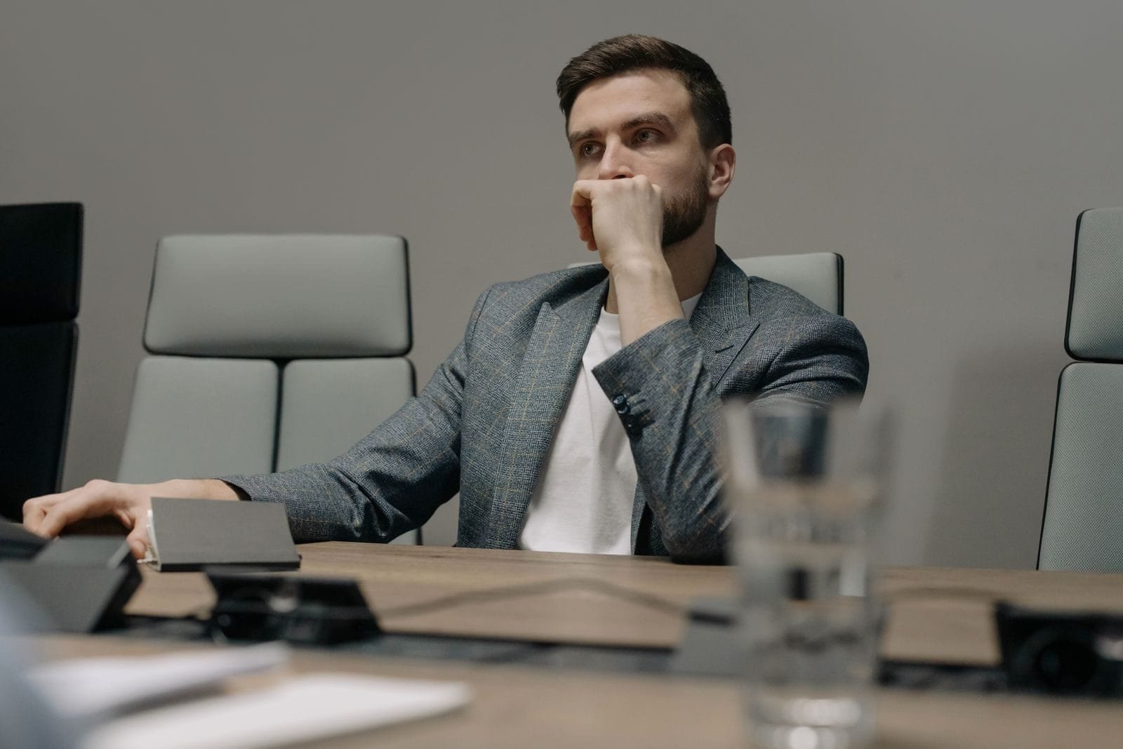 Improbidade exige intenção: a importância do dolo na responsabilização do gestor 1 A contemplative businessman sitting at a meeting table in a modern office setting.
