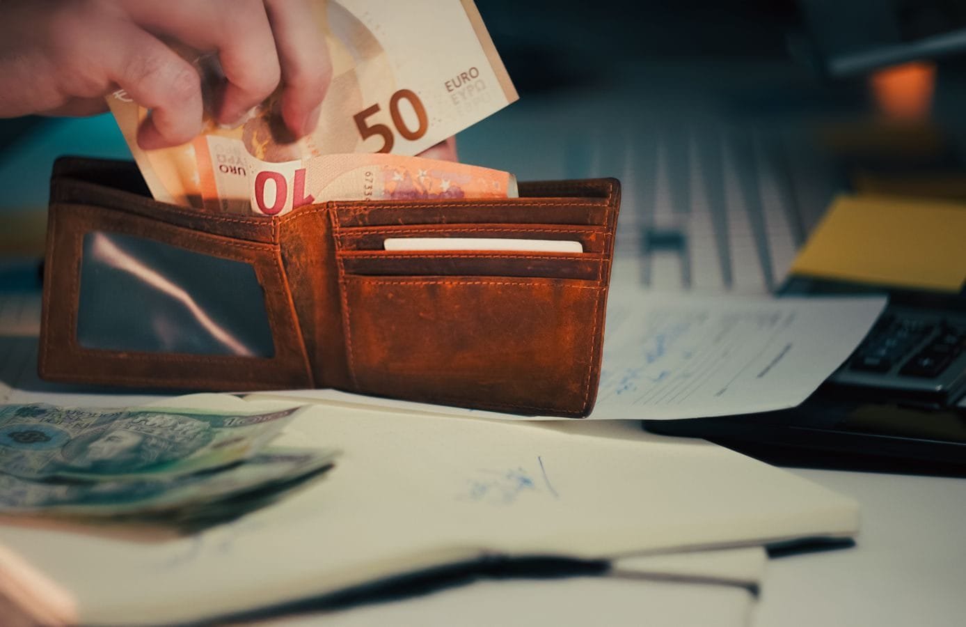 Incorporação da gratificação do bancário e a Reforma de 2017 1 A wallet with euro banknotes and documents on an office desk, symbolizing finance and budgeting.