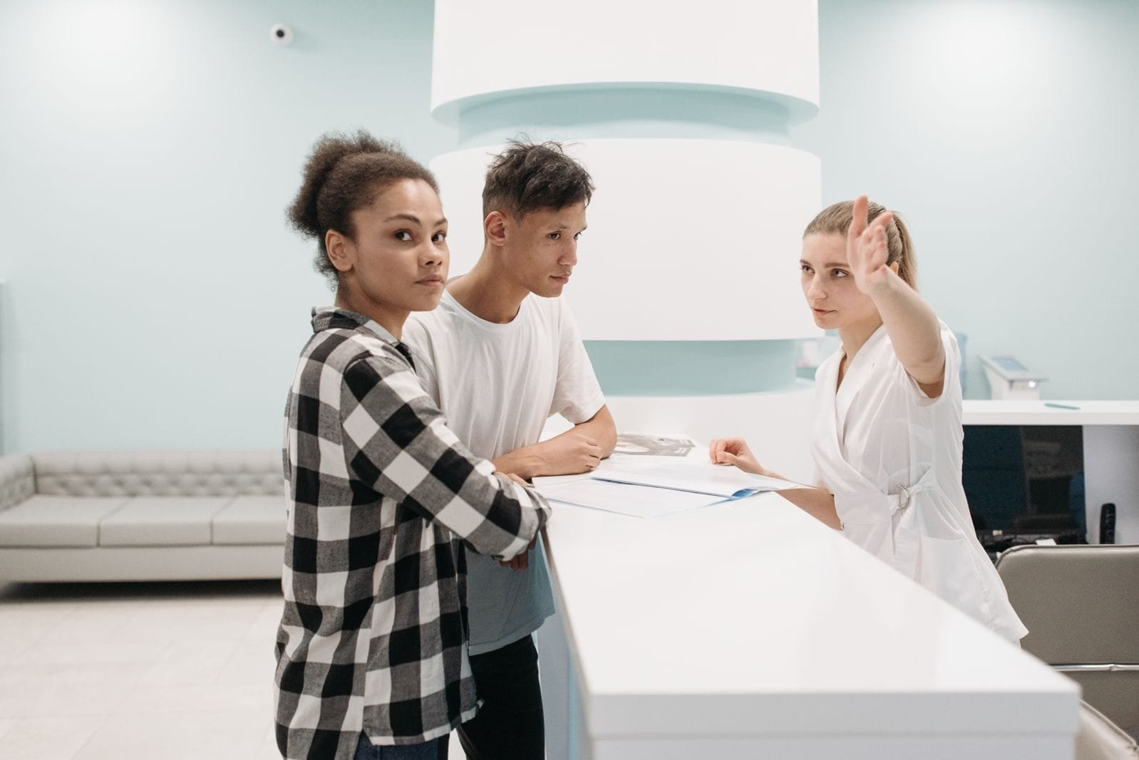 INSS Atende 235 Trabalhadores Rurais em Mutirão em Linhares 1 Two patients at hospital reception desk interacting with receptionist in white attire.