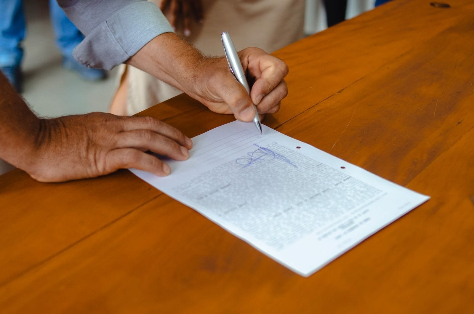 INSS bate recorde histórico de concessão com 890 mil benefícios em um único mês (referente a março), anunciado em maio de 2026 1 Close-up of a person signing a document on a wooden table, emphasizing detail and focus.