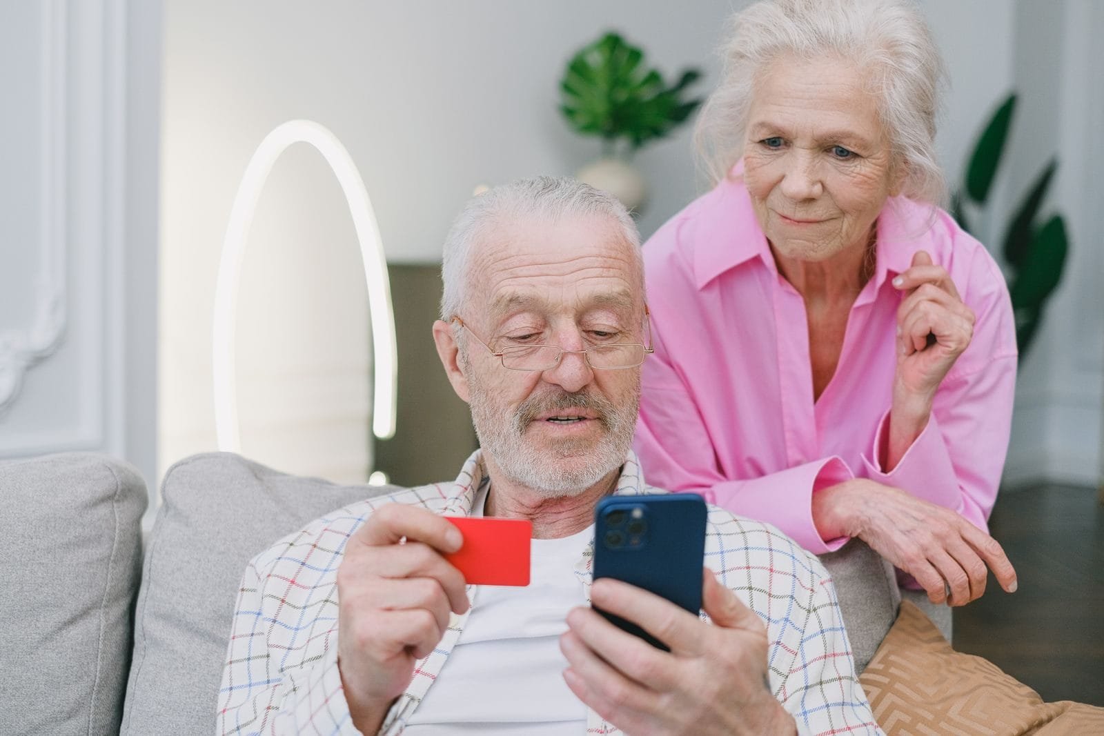 INSS Bloqueia Consignado do C6: 320 Mil Contratos Afetados 1 Elderly couple using smartphone and credit card for online shopping at home.