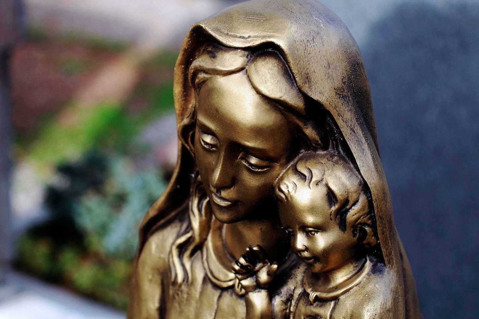 Bronze statue depicting a serene mother and child, capturing a moment of tenderness in Augsburg cemetery.