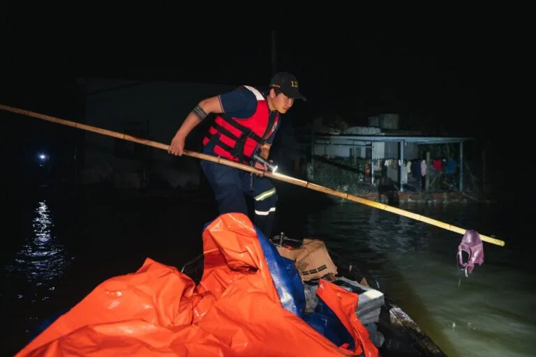 A rescue worker in Phú Yên, Vietnam, aids flood victims during nighttime operations.