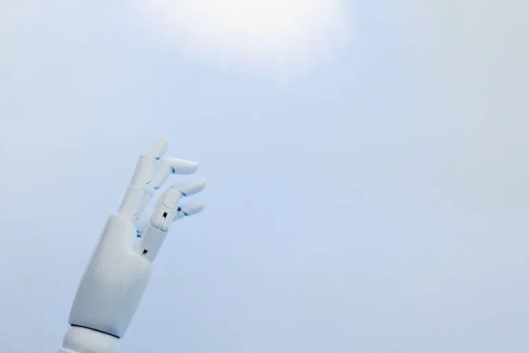 A robotic hand reaching towards a bright light on a white background symbolizing innovation.