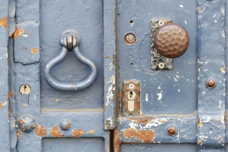 Interdição e apreensão: o que fazer quando a fiscalização fecha o seu negócio 2 Close-up of a weathered blue door with a vintage knocker and rusty lock.