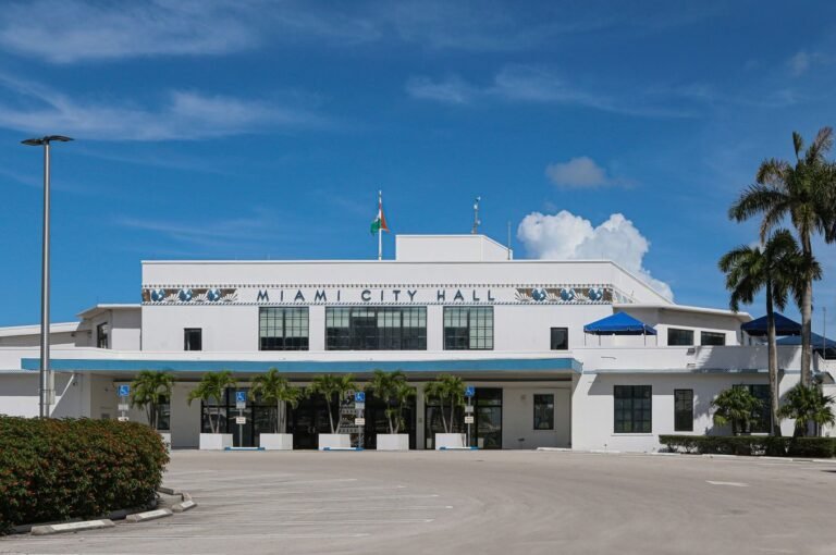 Front view of Miami City Hall with palm trees under a clear blue sky.