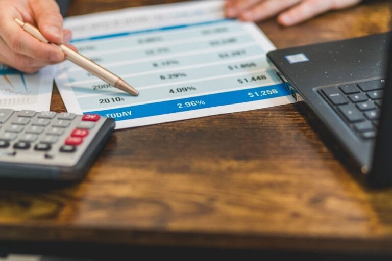 Juros Abusivos em Financiamento: Como Identificar 7 Mao com caneta analisando taxas de juros em documento financeiro ao lado de calculadora