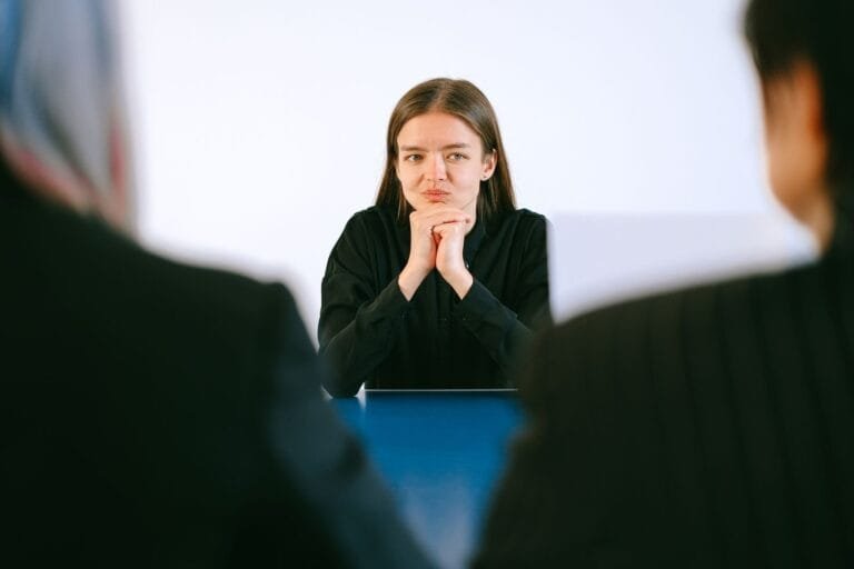 Justa causa: o que o empregador precisa provar para aplica-la 6 A woman in a job interview facing two people at an office table, focusing intently.