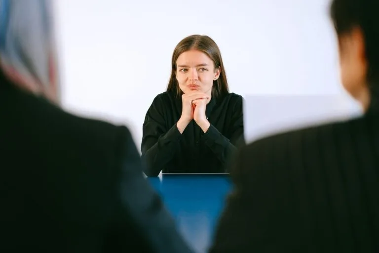 Justa causa: o que o empregador precisa provar para aplica-la 3 A woman in a job interview facing two people at an office table, focusing intently.