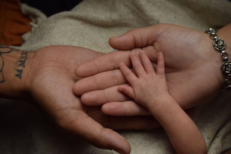 Close-up of adult and baby hands symbolizing family connection and love.