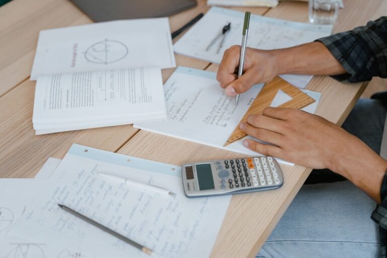 Malha fina do Imposto de Renda: por que cai e como regularizar a situacao 2 A student engaged in solving math problems using a calculator and stationery on a desk.