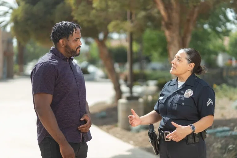 Medidas Protetivas de Urgência: Como Solicitar 2 A police officer engaging warmly with a community member outdoors on a sunny day.