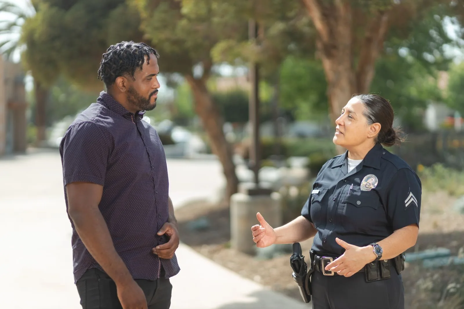 Medidas Protetivas de Urgência: Como Solicitar 1 A police officer engaging warmly with a community member outdoors on a sunny day.