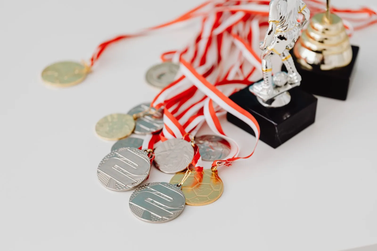 Meu INSS é Finalista em Prêmio de Inovação em 2026 1 A varied collection of silver and gold medals alongside trophies on a white surface, showcasing achievement.