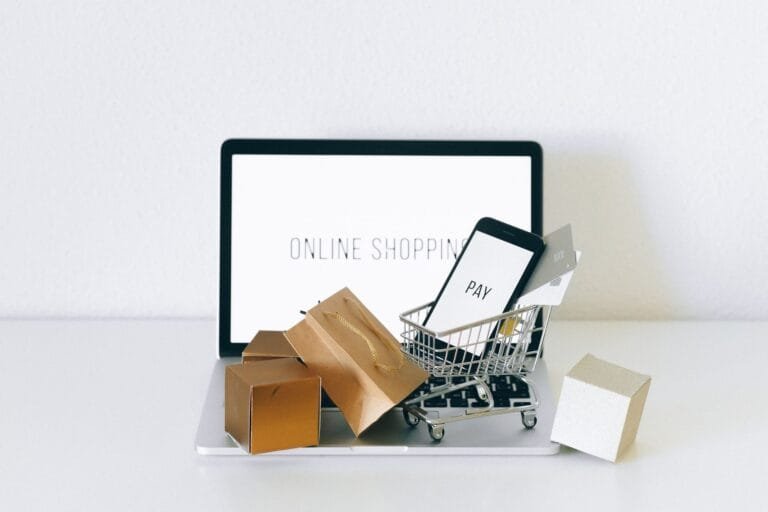 Notebook com carrinho de compras e dispositivos de pagamento, tema de multa de fidelidade em contratos de consumo