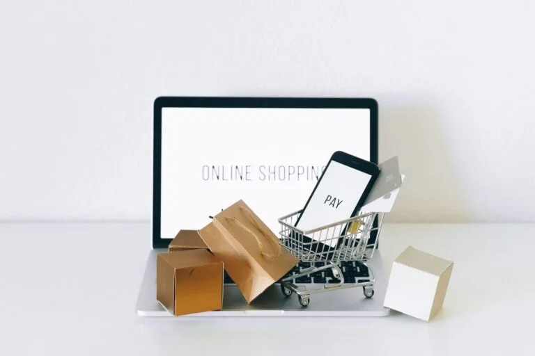 Notebook com carrinho de compras e dispositivos de pagamento, tema de multa de fidelidade em contratos de consumo