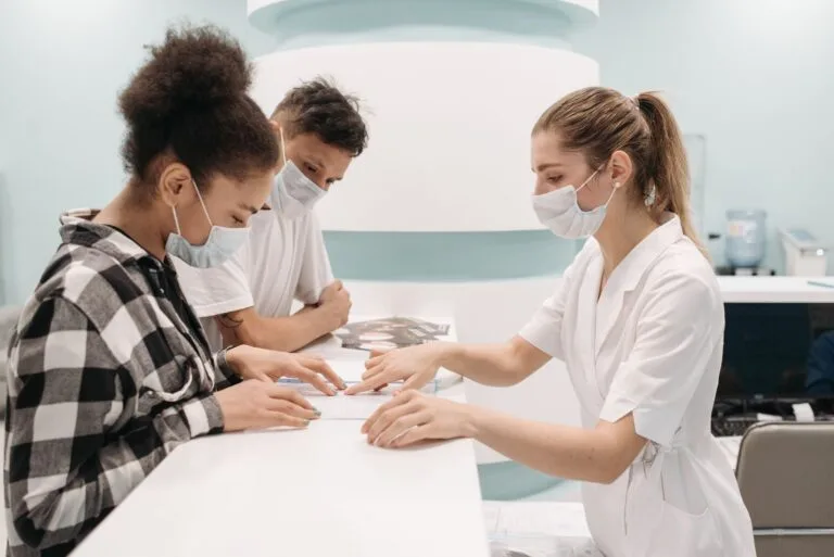 Mutirão do INSS faz 22.837 atendimentos em fim de semana de abril 2 A healthcare professional in a medical setting assists patients at a clinic desk, emphasizing care and teamwork.