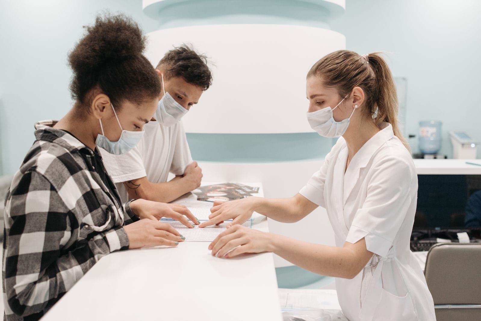 Mutirão do INSS faz 22.837 atendimentos em fim de semana de abril 1 A healthcare professional in a medical setting assists patients at a clinic desk, emphasizing care and teamwork.