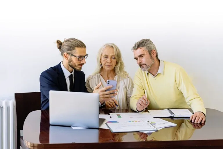 Novas regras do consignado do INSS entram em vigor em 19/05/2026 e reduzem a margem consignável de 45% para 40% 5 Three individuals collaborating on financial documents during a business meeting.