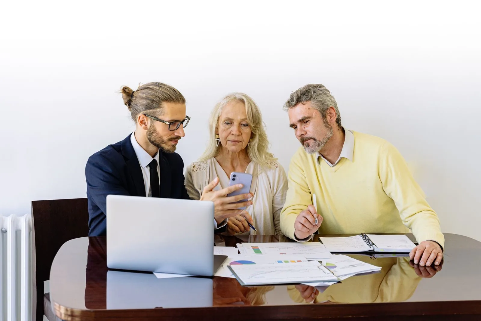 Novas regras do consignado do INSS entram em vigor em 19/05/2026 e reduzem a margem consignável de 45% para 40% 1 Three individuals collaborating on financial documents during a business meeting.