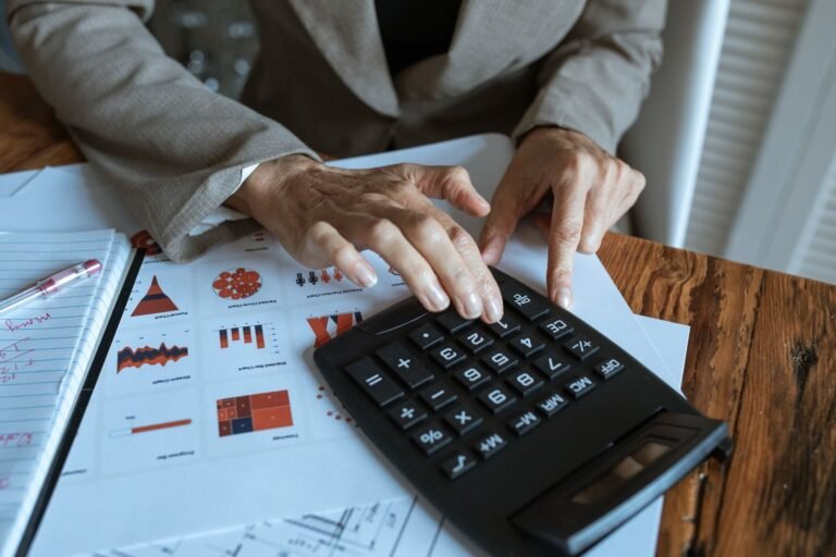 O que e a substituicao tributaria do ICMS e como ela afeta o preco final 14 A businessman using a calculator to analyze financial charts and graphs on a desk.